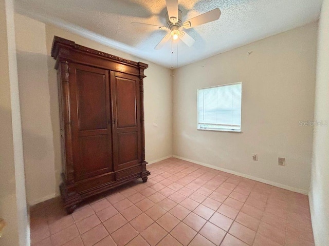 spare room with ceiling fan, light tile patterned flooring, and a textured ceiling