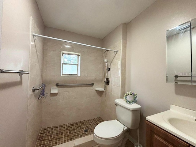 bathroom with a tile shower, vanity, and toilet