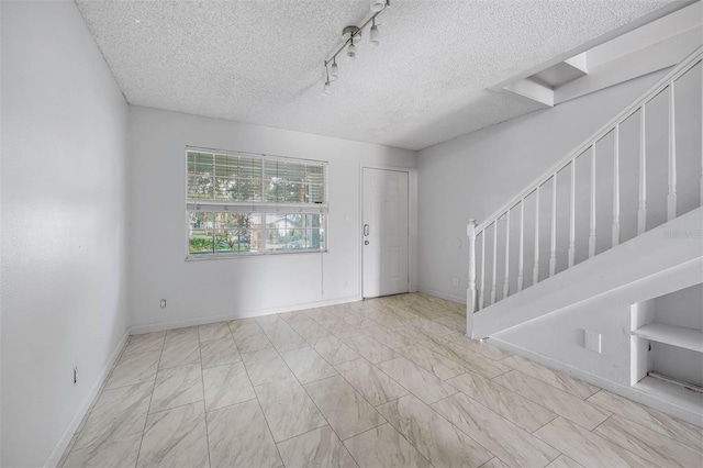 entrance foyer featuring rail lighting and a textured ceiling