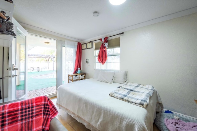 tiled bedroom featuring ornamental molding and access to outside