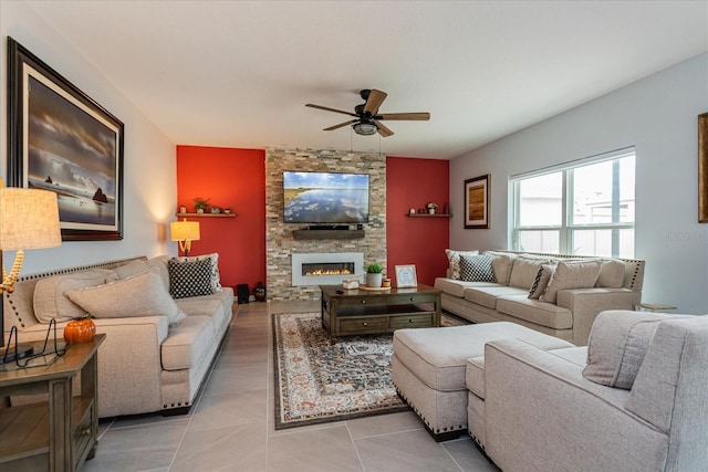 tiled living room featuring a stone fireplace and ceiling fan