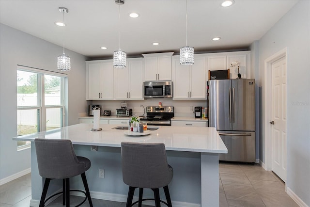 kitchen with decorative light fixtures, white cabinetry, stainless steel appliances, and a kitchen island with sink