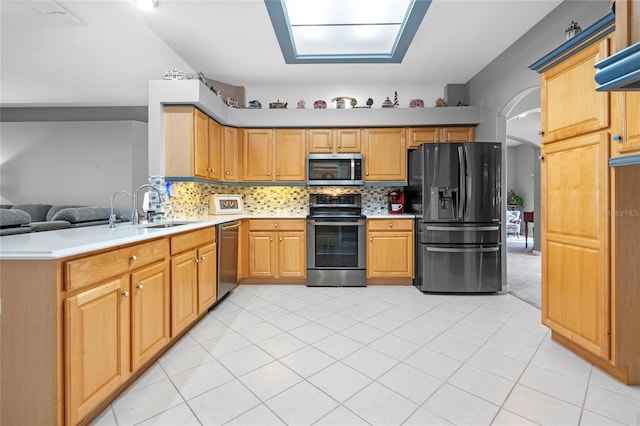 kitchen featuring sink, kitchen peninsula, decorative backsplash, light tile patterned flooring, and appliances with stainless steel finishes