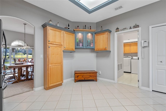 kitchen with independent washer and dryer, an inviting chandelier, light brown cabinetry, and light tile patterned flooring