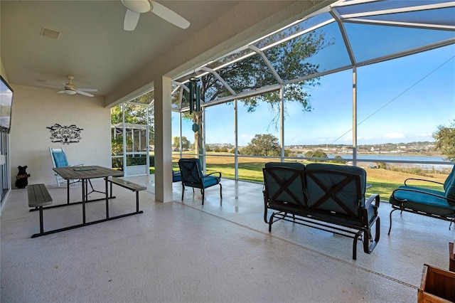 view of patio / terrace with a water view, ceiling fan, and a lanai