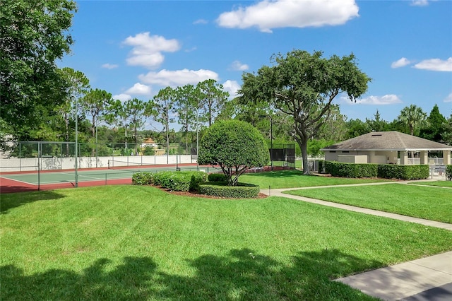 view of home's community with a lawn and tennis court