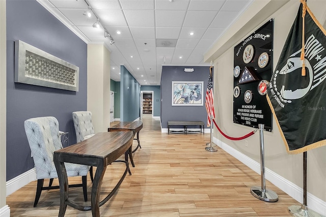 interior space with crown molding, a drop ceiling, light hardwood / wood-style floors, and track lighting