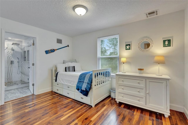 bedroom featuring connected bathroom, dark hardwood / wood-style flooring, and a textured ceiling