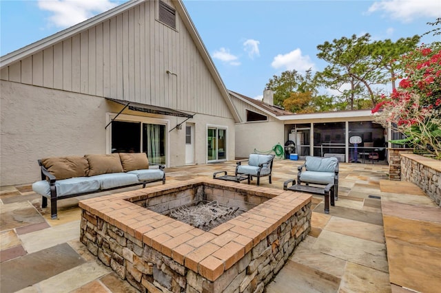 view of patio / terrace with a sunroom and an outdoor fire pit