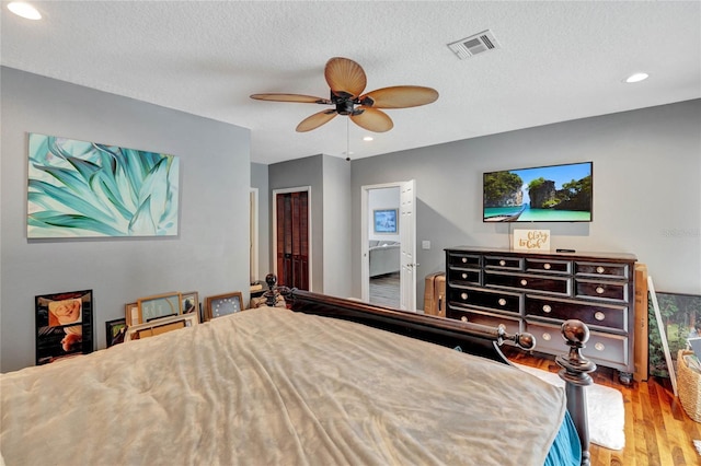 bedroom featuring a textured ceiling, hardwood / wood-style flooring, ceiling fan, and ensuite bathroom