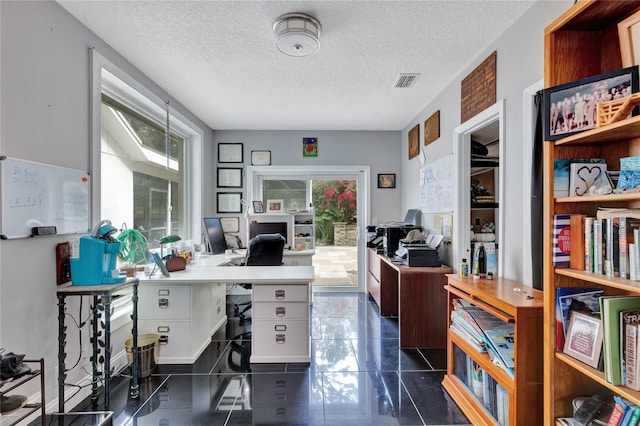 home office featuring dark tile patterned floors and a textured ceiling