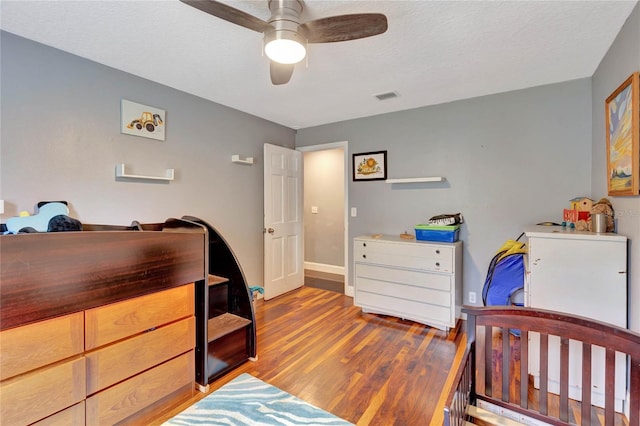 bedroom with ceiling fan, light hardwood / wood-style flooring, and a textured ceiling