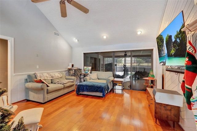 living room featuring wood-type flooring, a textured ceiling, vaulted ceiling, and ceiling fan