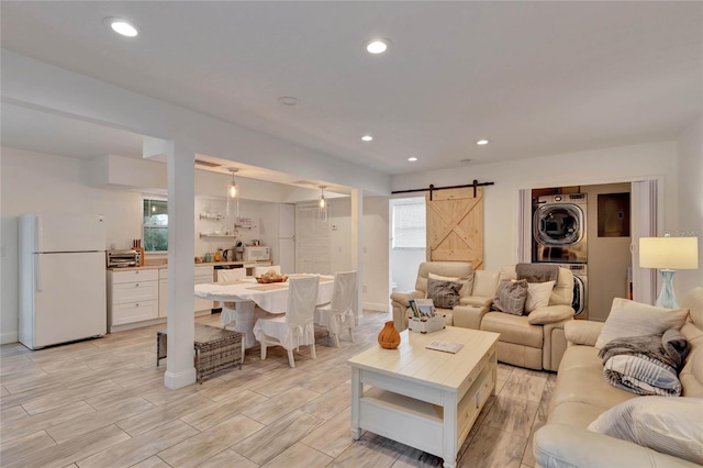 living room with stacked washer / drying machine and a barn door