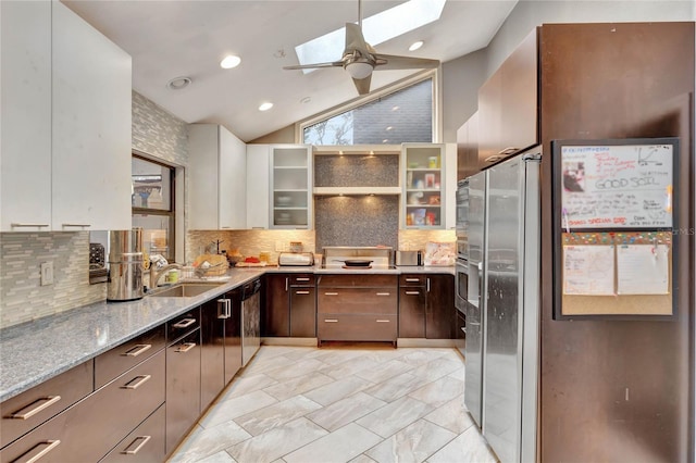 kitchen with dark brown cabinetry, backsplash, white cabinetry, and light stone counters