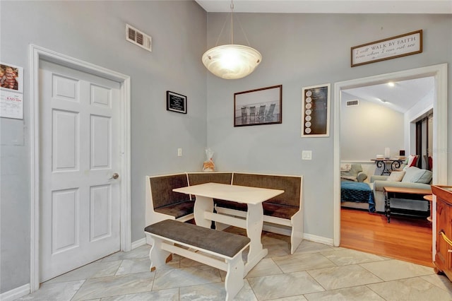 dining room with light tile patterned floors and vaulted ceiling