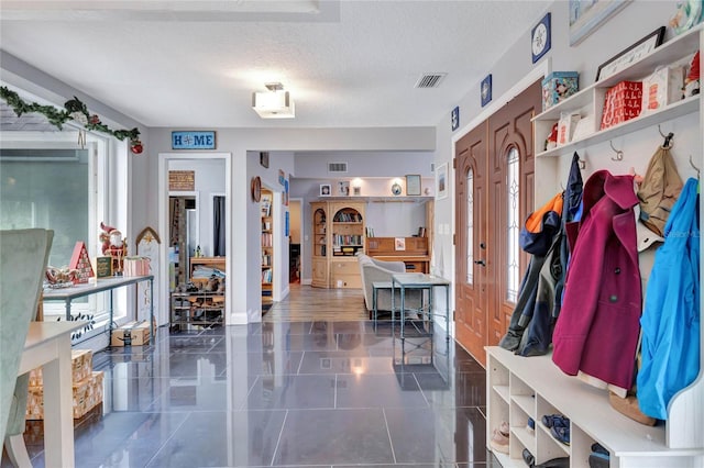 mudroom featuring dark tile patterned flooring and a textured ceiling