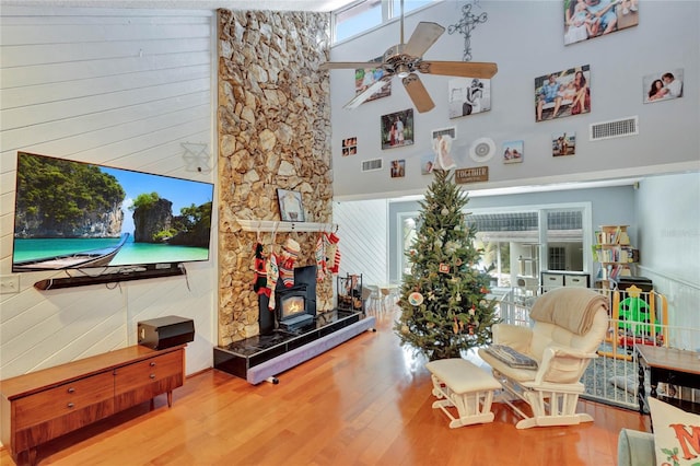 living room featuring a towering ceiling, hardwood / wood-style flooring, a wood stove, and wooden walls