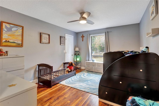 bedroom with ceiling fan, hardwood / wood-style floors, and a textured ceiling