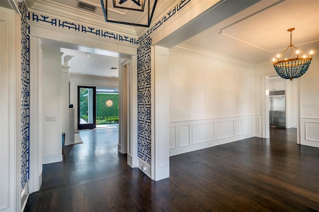 hall with dark hardwood / wood-style flooring, crown molding, and a chandelier