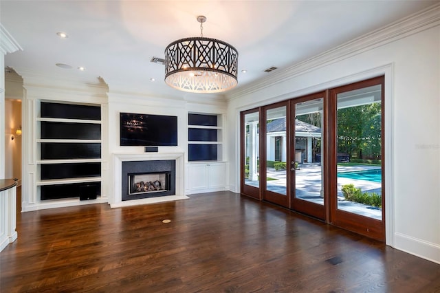 unfurnished living room featuring crown molding, a notable chandelier, and built in shelves