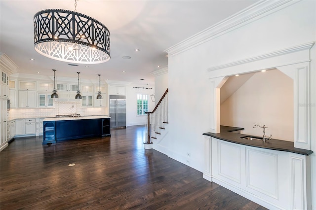 bar with pendant lighting, white cabinetry, sink, built in refrigerator, and crown molding