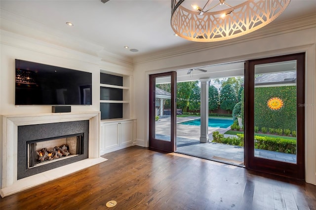 unfurnished living room featuring built in shelves, dark hardwood / wood-style flooring, and crown molding