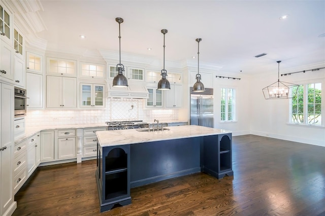 kitchen featuring decorative light fixtures, an island with sink, white cabinets, light stone counters, and stainless steel appliances