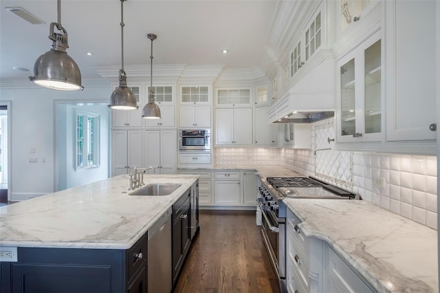 kitchen featuring sink, appliances with stainless steel finishes, white cabinetry, an island with sink, and decorative light fixtures