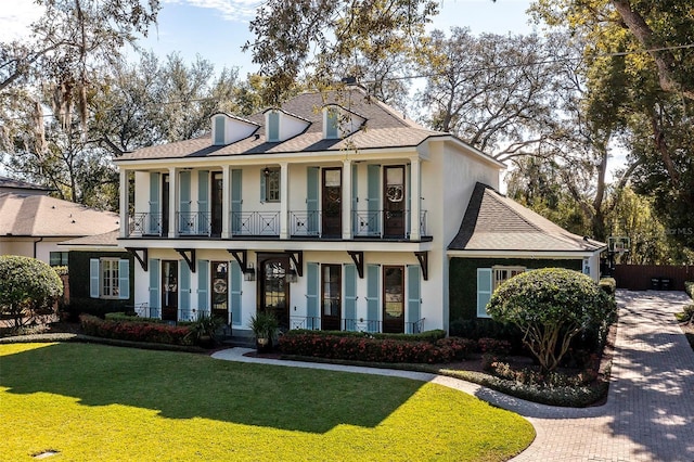 view of front of house with a balcony and a front lawn