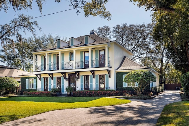 view of front facade featuring a balcony and a front yard