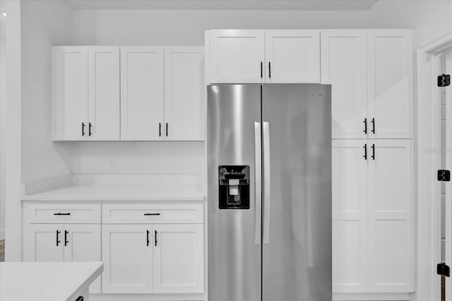 kitchen featuring light stone countertops, white cabinets, and stainless steel fridge