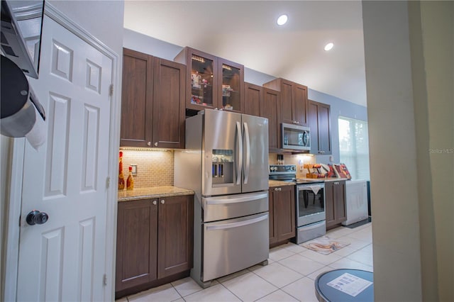 kitchen with appliances with stainless steel finishes, tasteful backsplash, light tile patterned floors, and light stone counters