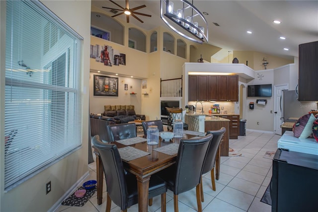 tiled dining room with ceiling fan and a high ceiling