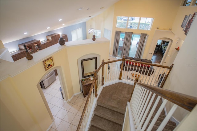 stairs with tile patterned floors and a high ceiling