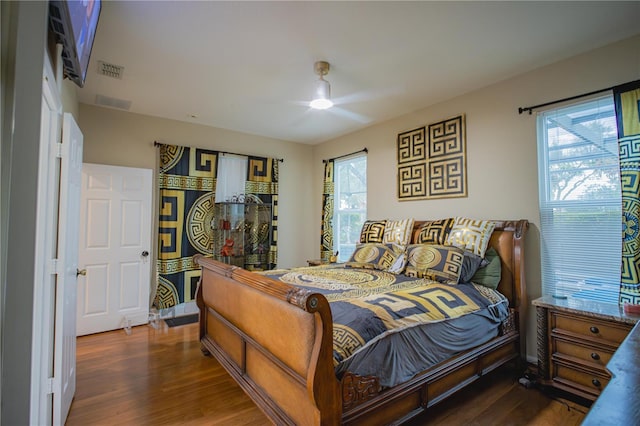 bedroom with multiple windows, ceiling fan, and dark wood-type flooring