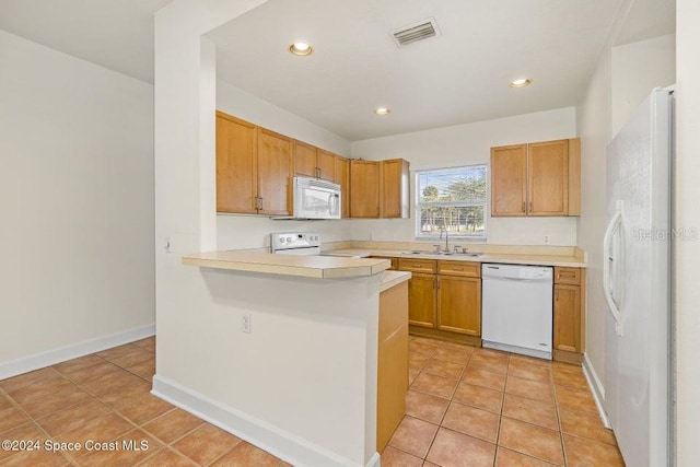 kitchen featuring kitchen peninsula, sink, light tile patterned floors, and white appliances