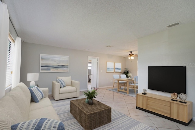 living room with light tile patterned floors, a textured ceiling, and ceiling fan