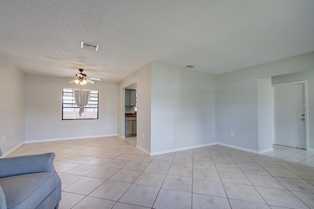 unfurnished living room with a textured ceiling, ceiling fan, and light tile patterned flooring