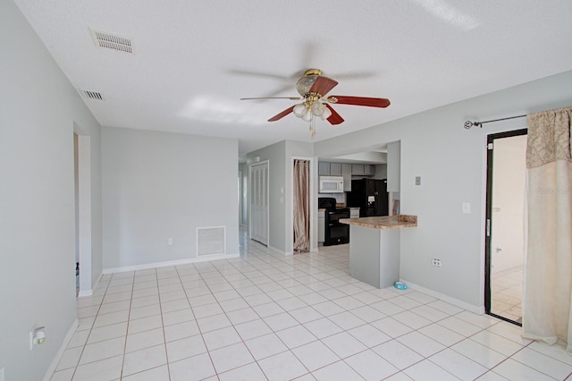 tiled empty room with ceiling fan and a textured ceiling