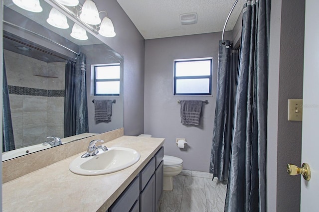 bathroom with a textured ceiling, vanity, toilet, and a healthy amount of sunlight