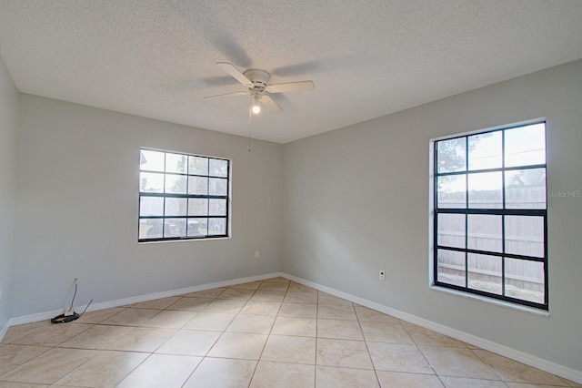 unfurnished room featuring a wealth of natural light, ceiling fan, light tile patterned flooring, and a textured ceiling