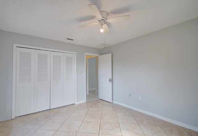 unfurnished bedroom featuring light tile patterned floors, a textured ceiling, a closet, and ceiling fan