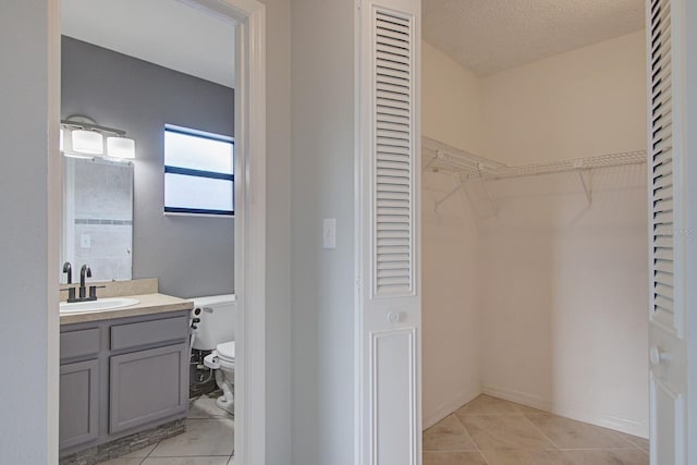 bathroom featuring vanity, a textured ceiling, toilet, and tile patterned flooring