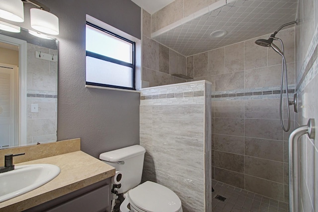 bathroom featuring tiled shower, vanity, and toilet