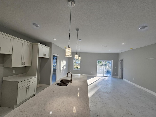 kitchen with light stone counters, a textured ceiling, pendant lighting, white cabinetry, and sink