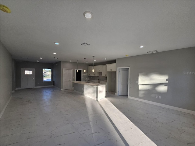 kitchen with decorative light fixtures, white cabinets, a kitchen island, and tasteful backsplash