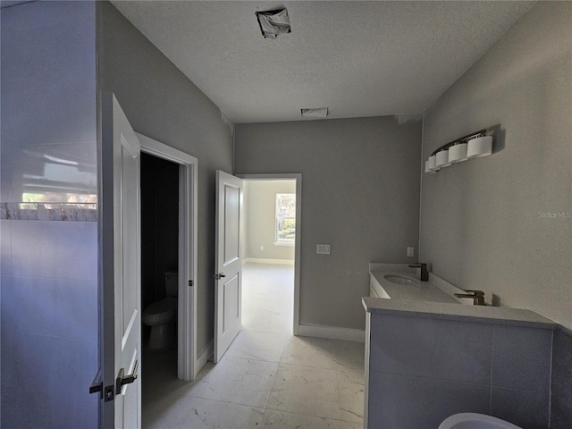 bathroom with toilet, vanity, and a textured ceiling