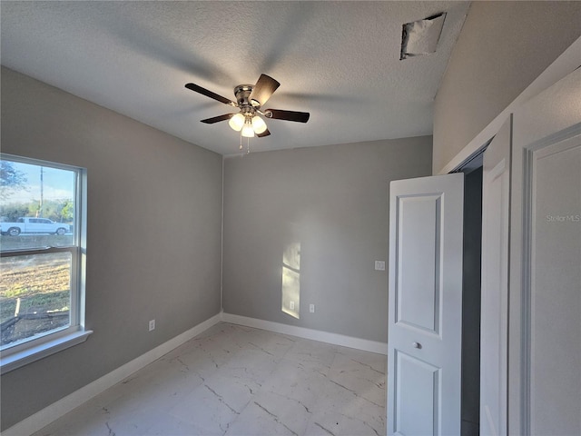 unfurnished bedroom with ceiling fan and a textured ceiling