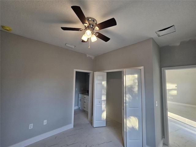 unfurnished bedroom with ceiling fan, ensuite bath, and a textured ceiling